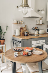 Sushi on wooden table in the kitchen. Scandinavian style. White wooden background. Bright kitchen interior. sushi with chopsticks. sushi on a plat. table setting for dinner. modern interior. 