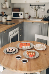 Sushi on wooden table in the kitchen. Scandinavian style. White wooden background. Bright kitchen interior. sushi with chopsticks. sushi on a plat. table setting for dinner. modern interior. 