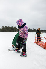 Girl Putting Snowshoes On While on Lake