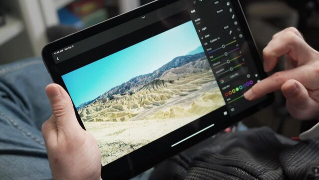 Photographer Editing Pictures on a Tablet Screen Adjusting Settings