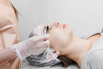 Eyelash procedure with clinic master and a client in a beauty salon