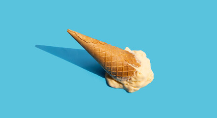 Melting ice cream balls with waffle cone on blue background.