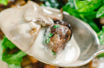 An appetizer of chestnuts, mushrooms and veal liver. A dish of Mediterranean cuisine, Corsican cuisine. Food tasting with a spoon. Macro shooting