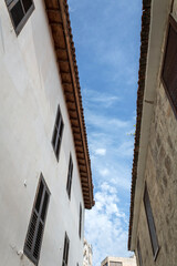 Fototapeta na wymiar Blue sky with white clouds between two old houses