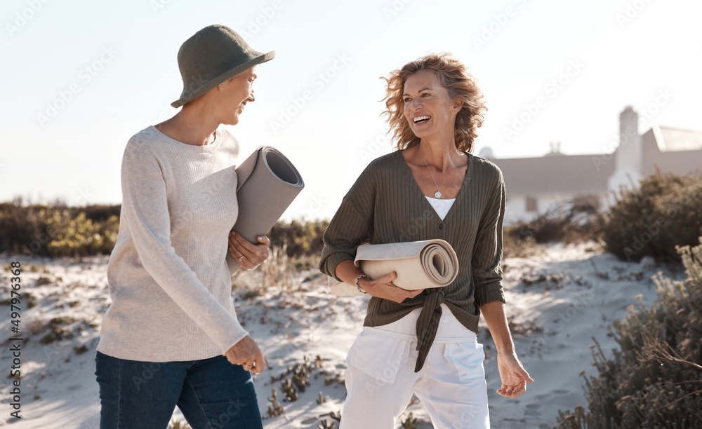 Poster Loving life on the beach. Cropped shot of two attractive mature woman walking with their on the beach.