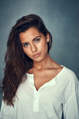 Fototapeta premium Fixing you with a beautiful stare. Portrait of a beautiful young woman posing against a gray background in studio.