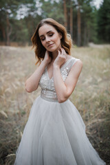 Naklejka premium A beautiful, satisfied bride in a pine forest poses.