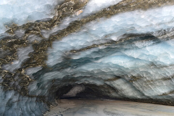 Walls of centuries-old ice with veins of soil and rocks in an ice cave in Alaska's Castner Glacier.