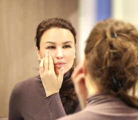 Obraz na płótnie Canvas Woman looking in the mirror Applying the cream..Magic anti-aging cream.