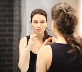 Woman looking in the mirror Applying the cream..Magic anti-aging cream.