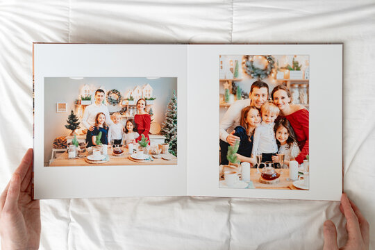 Hands With Opened Photobook On A White Background. Family Photo Shoot 