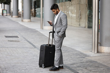 Hes ready for that business trip. Shot of a young businessman using a phone in the city.