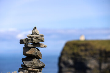 A stack of rocks with the O'Brien tower at the Cliffs of Moher out of focus in the background