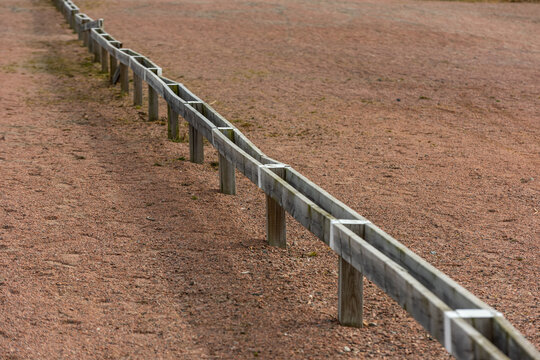 Low wooden barriers separating parking spots at a parking lot.
