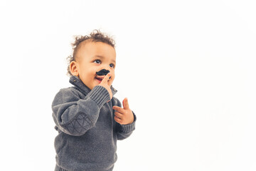 Funny happy hipster biracial kid touching his fake black mustache props over white background. High quality photo