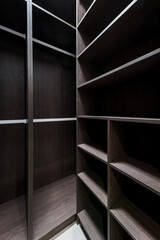 Wide wooden dressing room, interior of a modern house. Empty brown wooden shelves in the dressing room.