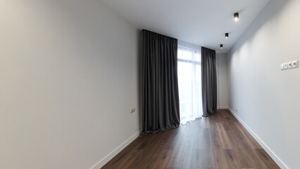 Bright white empty room, stylish interior design of the apartment. Designer gray curtains, brown parquet and white walls. Renovated apartment.