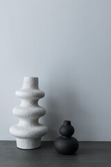 Home interior with decor elements. Black photo frame, white and black handmade decorative vases, interior decoration