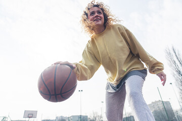 Excited young European woman plays basketball on the sports field, looking up copy space medium full shot . High quality photo - Powered by Adobe