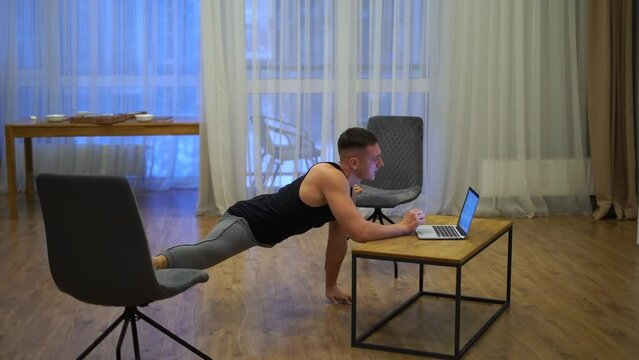 Flexible man work on laptop and doing split at home. Concept of willpower, motivation and passion