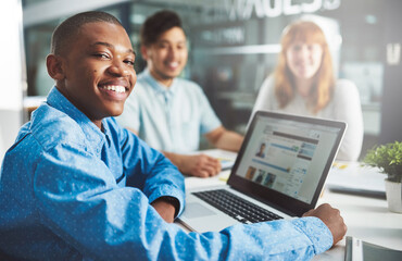 Were committed to keeping this office paperless. Cropped portrait of a young businessman working on a laptop in a boardroom with his colleagues.