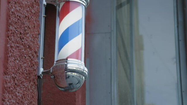 Advertising design on the facade of the building at the entrance. The movement of a rotating barbershop pole on the street. Attention-grabbing street advertising.