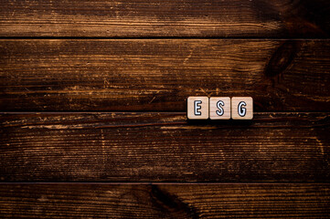 There is word cube formed the word ESG. It's placed on an wood board. Copy space available.