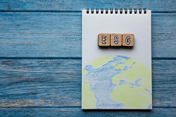 There is word cube formed the word ESG. It's placed on an wood board with a illustration of the earth. Copy space available.	There is word cube formed the word ESG. It's placed on an wood board with a