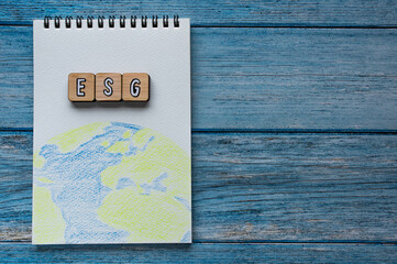 There is word cube formed the word ESG. It's placed on an wood board with a illustration of the earth. Copy space available.	There is word cube formed the word ESG. It's placed on an wood board with a