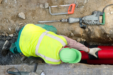 worker installing hdpe corrugated pipe with double wall strength at the construction site on street...