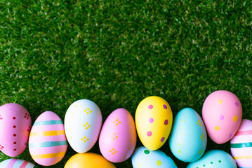 Easter background with colorful painted pink, blue, yellow Easter eggs and green grass. Top view with copy space. Easter holidays banner and header.