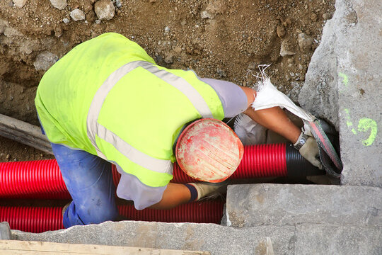 worker installing hdpe corrugated pipe with double wall strength at the construction site on street city