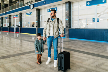 Father and son stand together at the train station waiting for the train to arrive.