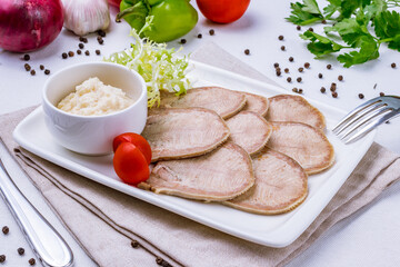 Beef tongue with horseradish on a white plate on white table