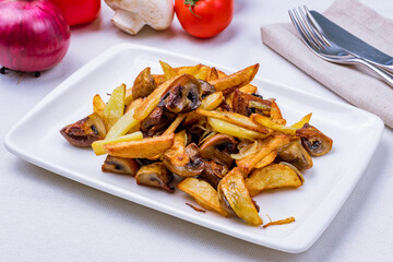 Fried potatoes with mushrooms on white plate
