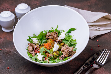 Salad with roast beef and poached egg on white plate
