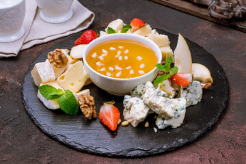 assorted European cheeses on black plate with honey