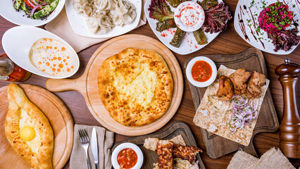 Georgian cuisine foodset from khachapuri, khinkali, pkhali, dolma, satsivi , ajara khachapuri, pork kebab and lula kebab top view on wooden table