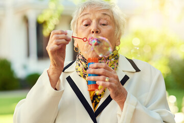 Shes on a playdate with her inner child. Shot of a fun-loving senior woman blowing bubbles outside...