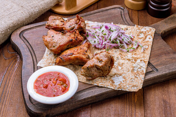 Kebab of pork on wooden board on wooden table