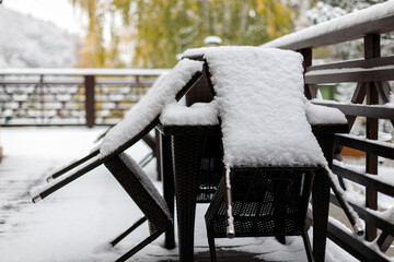 Freshly fallen snow on the furniture of the cafe's summer terrace, closing of the summer season