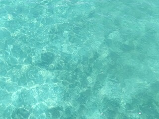 Beautiful crystal clear tropical water background with variegated aqua green color and abstract refracted sunlight