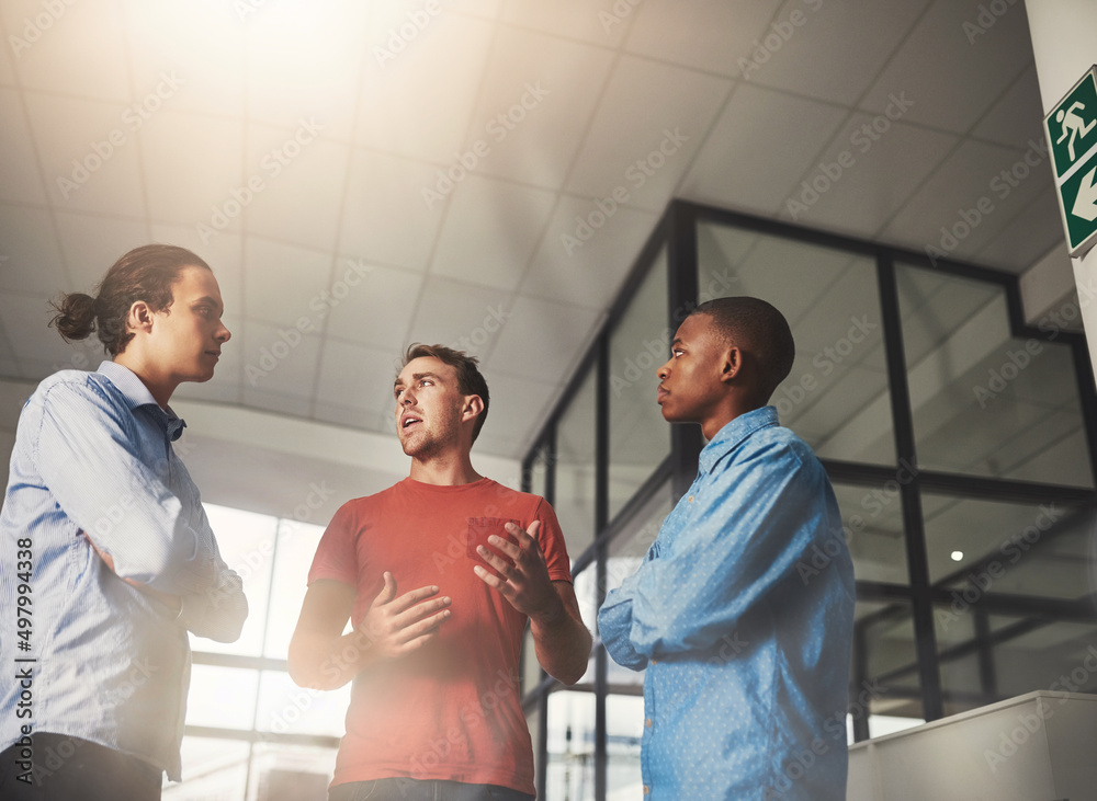 Poster sharing his thoughts with the team. shot of three colleagues having a discussion in an office.