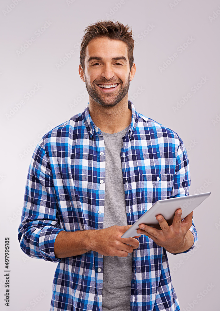 Poster checking in studio. studio shot of a handsome young man using a digital tablet against a gray backgr