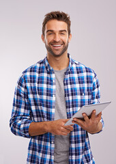 Checking in Studio. Studio shot of a handsome young man using a digital tablet against a gray background.