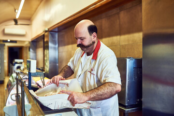 He takes pride in his business. Shot of a butcher at his store.