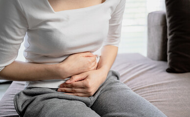 Young woman put her hand on her stomach because she had a very bad stomachache. menstrual pain, gastritis or diarrhoea. Healthcare medical concept.