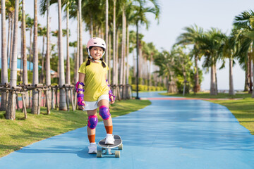 asian child or kid girl playing skateboard or surf skate in skating rink track and extreme sports...