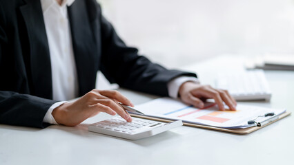 Close-up of business woman hands using a calculator to check company finances and earnings and budget.