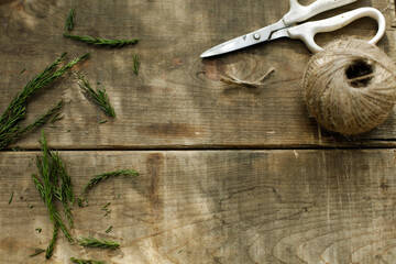 scissors, sisal twine and cedar leaves on old wooden craft table. crafting outdoor. space for copy.
